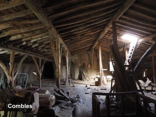Interior de un edificio antiguo con vigas de madera y desorden en el suelo.